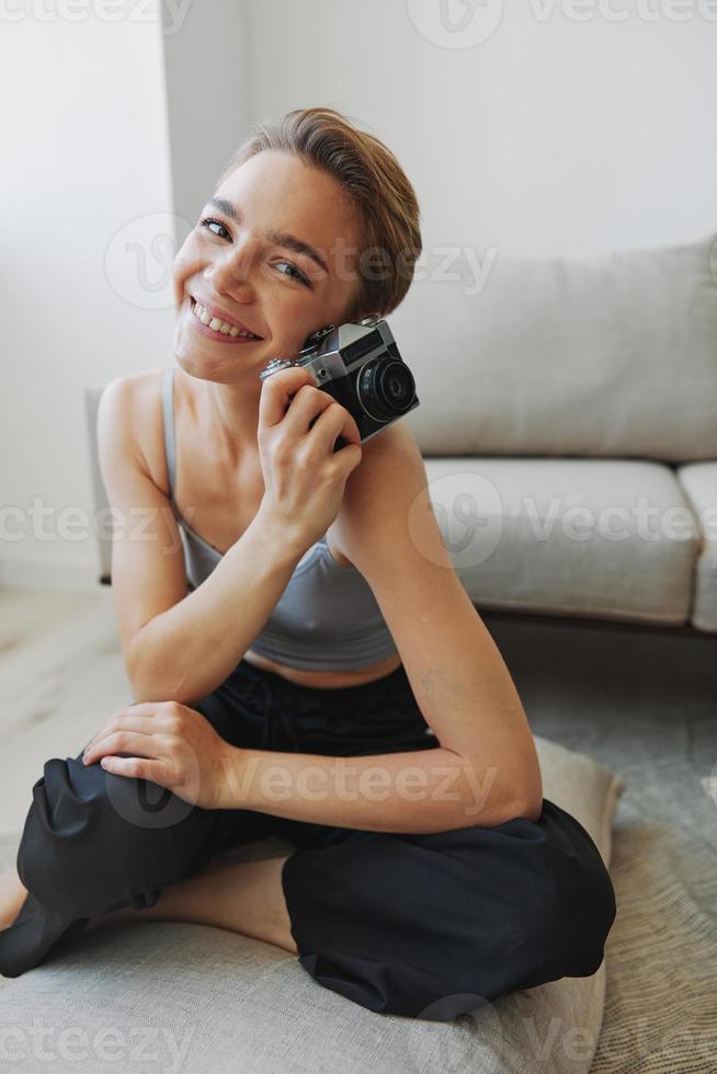 Happy smile woman holding an old camera and taking pictures of herself as a weekend photographer in home clothes with a short haircut hair without filters on a white background, free copy space photo