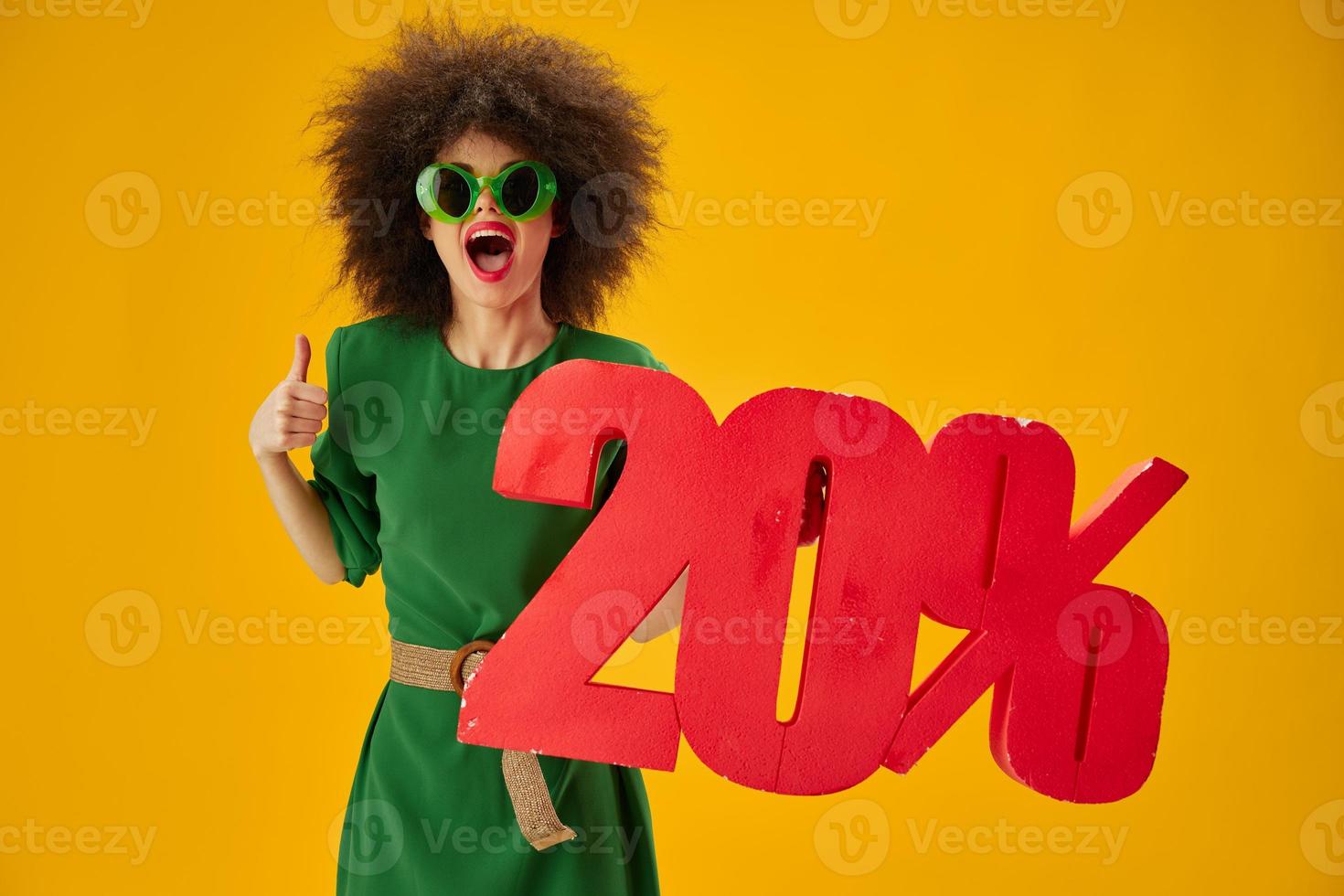 Portrait of a charming lady green dress afro hairstyle dark glasses twenty percent in hands color background unaltered photo