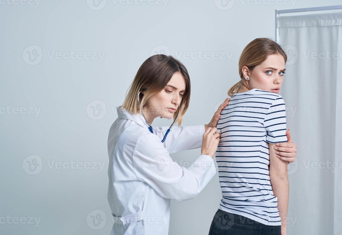 doctor woman in medical gown with stethoscope listens to patient's heart photo