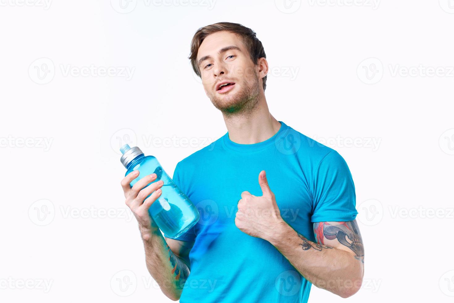 man in a blue t-shirt with a bottle of water in his hand on a white background Copy Space photo