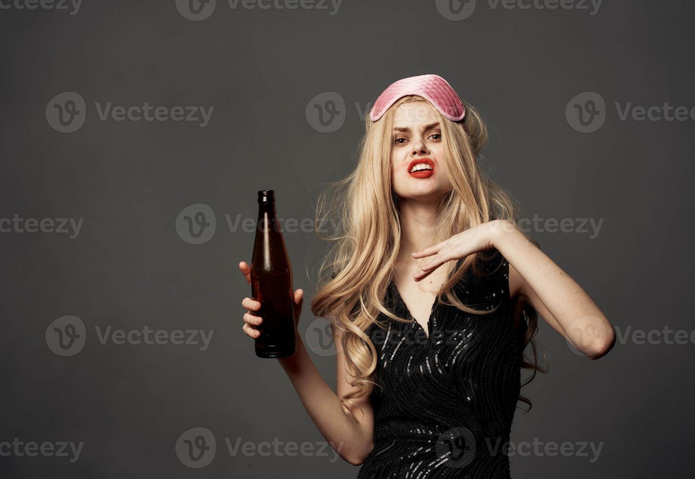 Beautiful blonde with a bottle of beer in her hand and a pink mask on her head photo