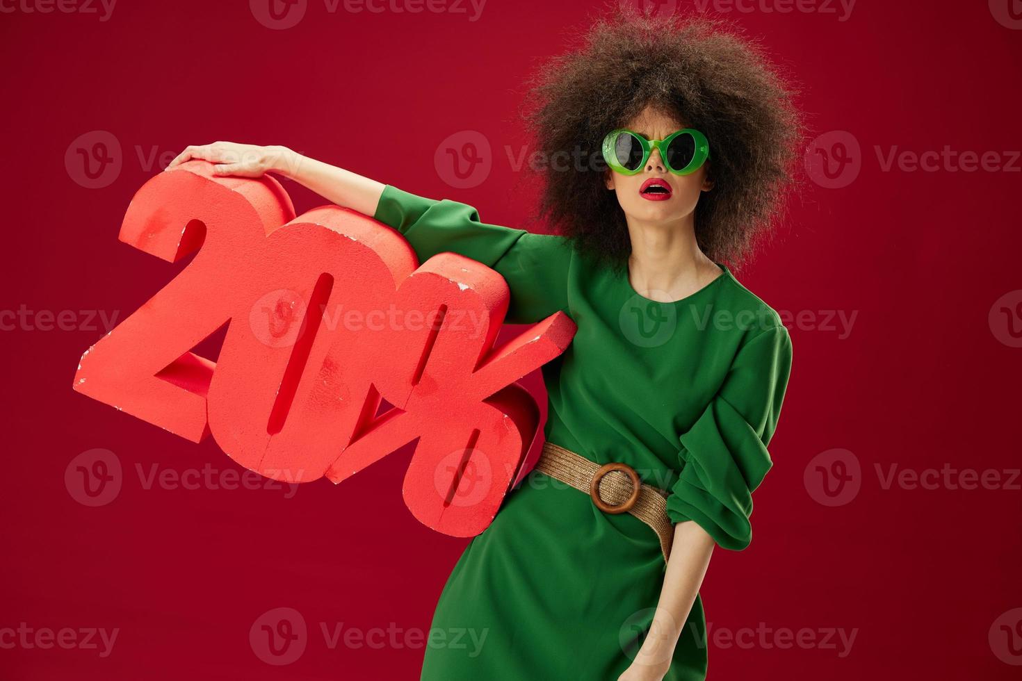 Positive young woman green dress afro hairstyle dark glasses twenty percent in hands studio model unaltered photo