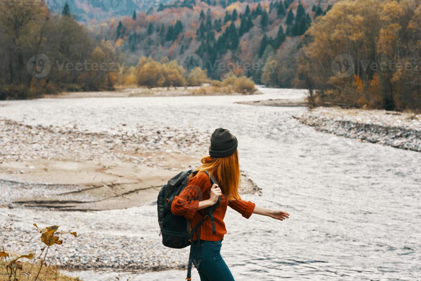 woman hiker backpacker by the river in the mountains in autumn model travel photo