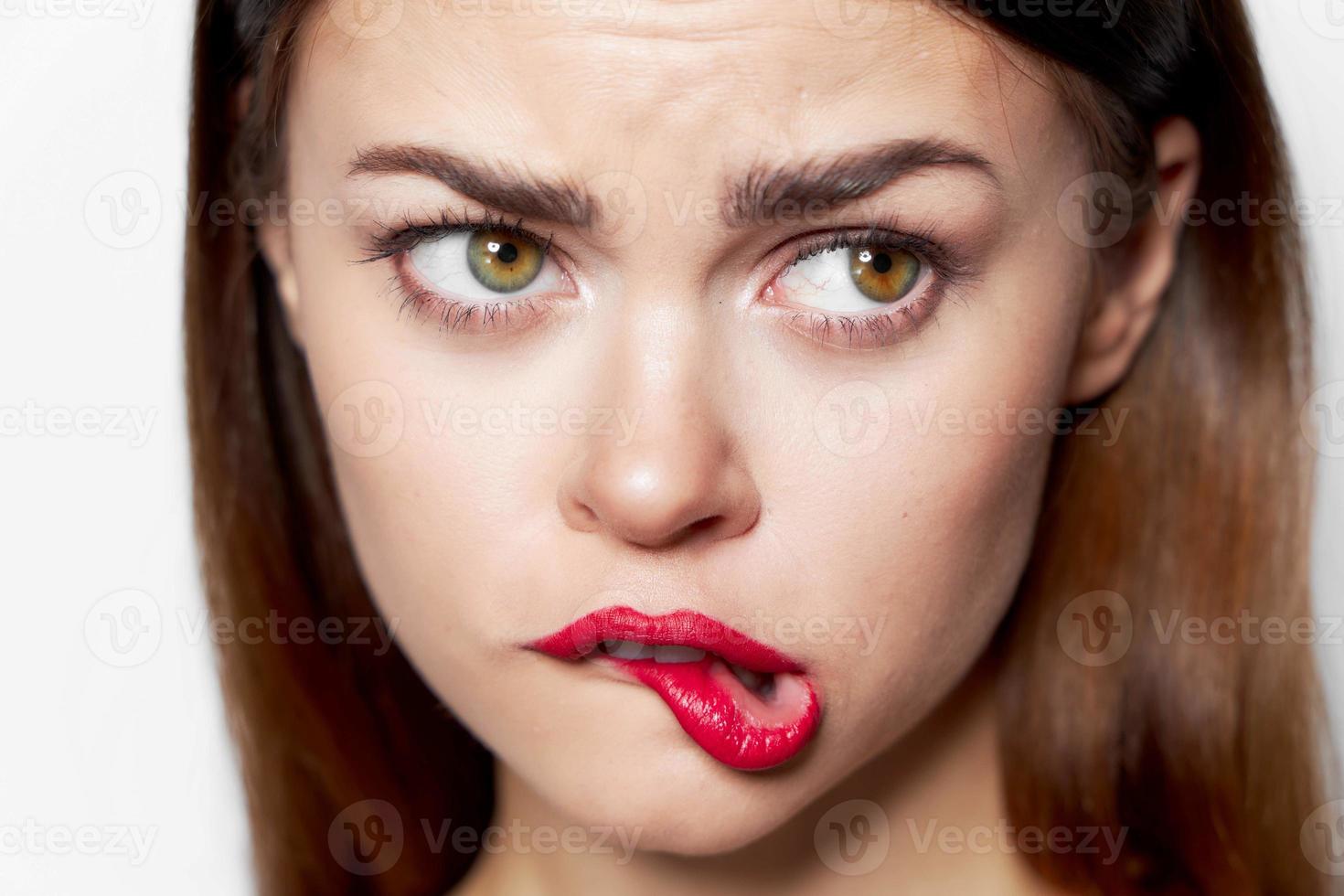 Close-up portrait of woman bites her lips red lipstick look photo