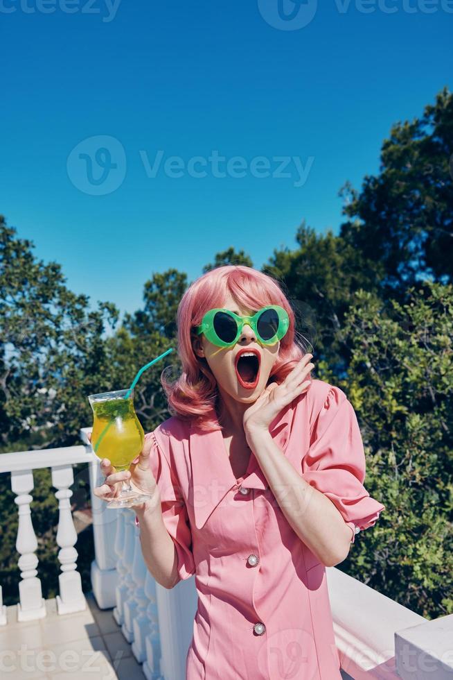 sorprendido mujer en verde lentes con cóctel al aire libre foto