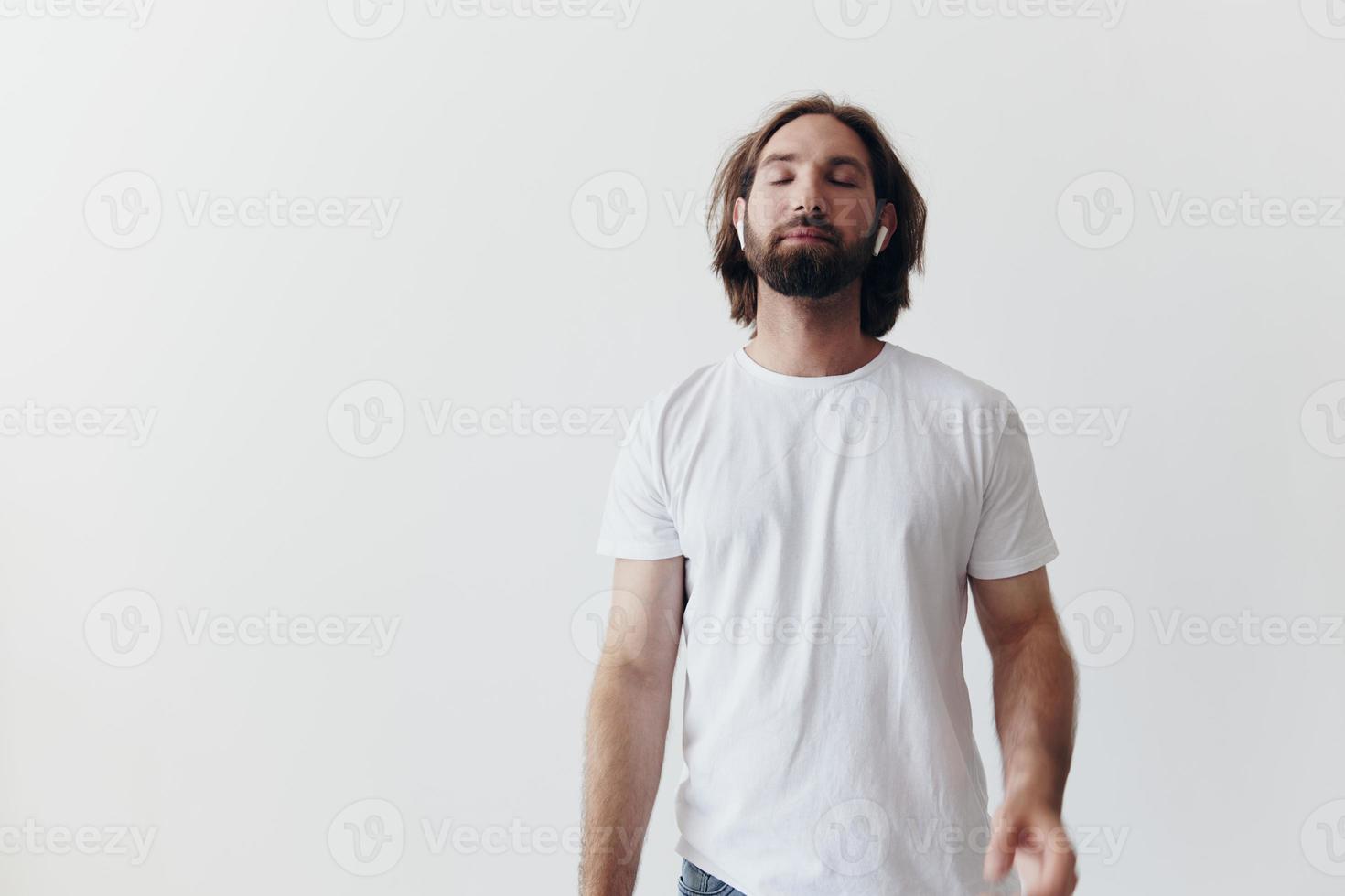 elegante hombre en un blanco camiseta con inalámbrico auriculares en su orejas teniendo divertido escuchando a música sonrisa en un blanco antecedentes estilo de vida foto