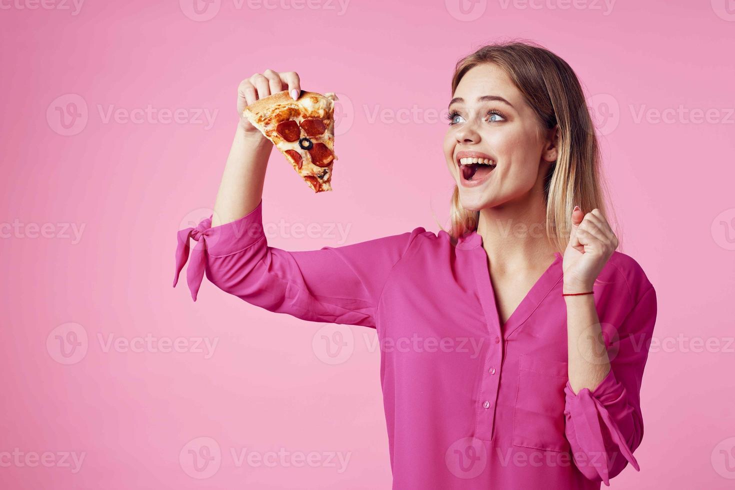 cheerful blonde with pizza in her hands junk food snack pink background photo