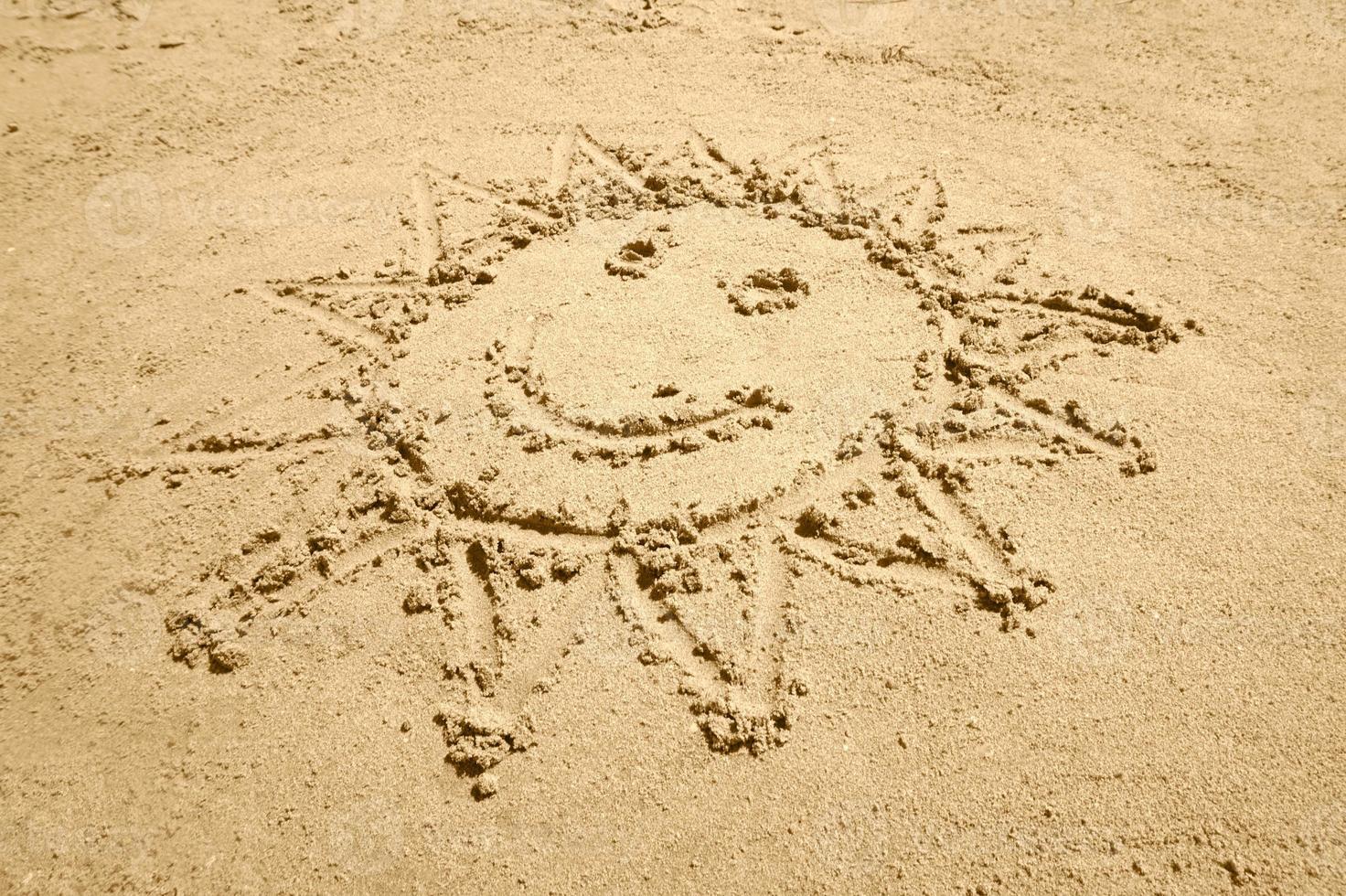 Sun Shape with a Smile Drawn on Sand photo