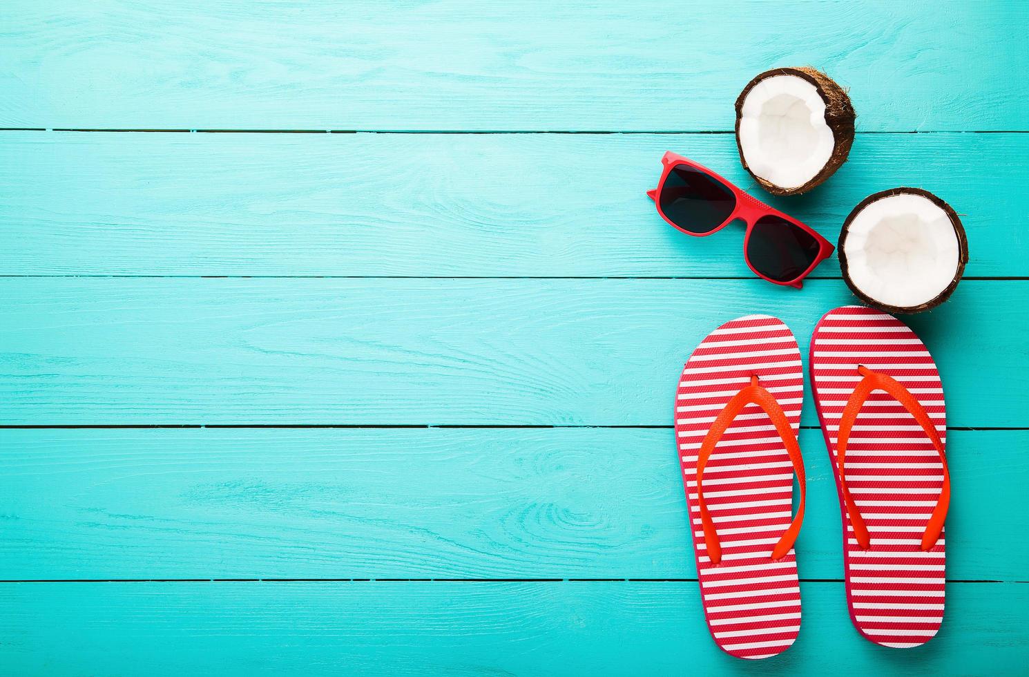 Flip flops, sunglasses and sea shell on blue wooden background. Copy space and fashion summer accessories. photo