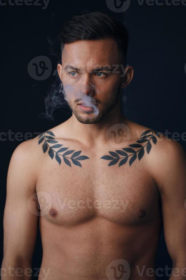 modelado instantáneas pensativo grave bronceado atractivo hermoso desnudo hombre pensando mira aparte de fumar posando aislado en negro estudio antecedentes. Moda oferta. Copiar espacio para anuncio. de cerca foto