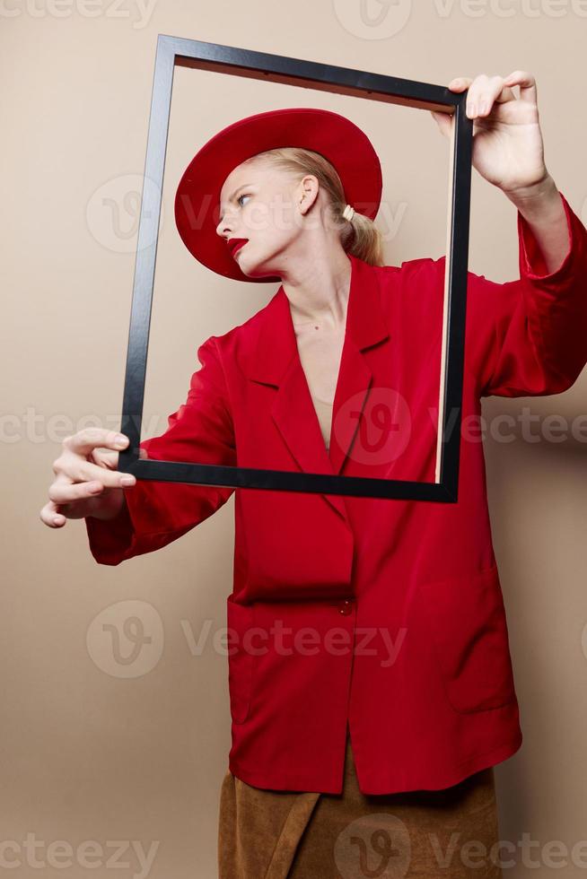 bonito mujer marco en mano en rojo sombrero y chaqueta aislado antecedentes foto