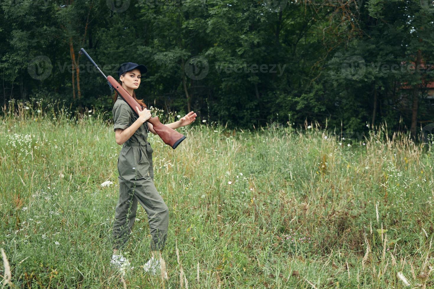 militar mujer caza en el campo con un arma en su hombro negro gorra foto