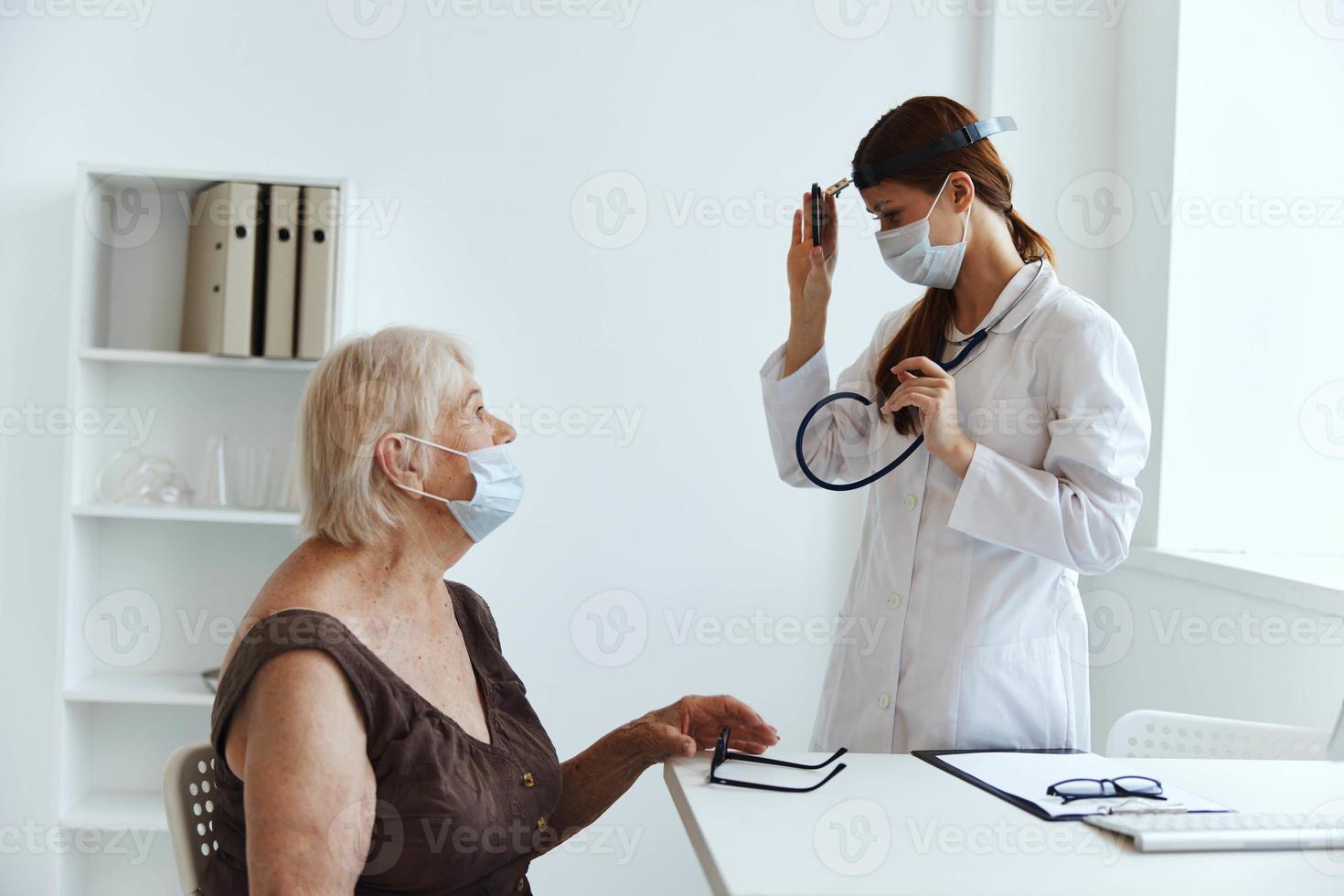 mayor mujer vistiendo un médico máscara en examen por un enfermero salud diagnósticos foto