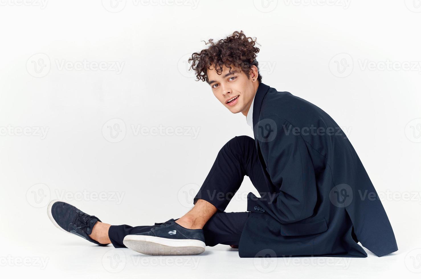 business man curly hair fun suit sitting on the floor light background photo