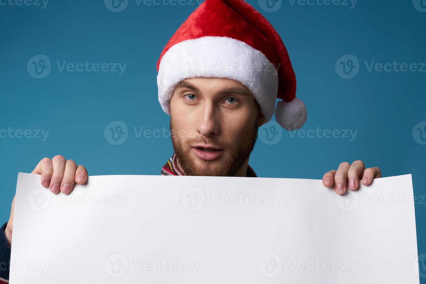 handsome man in a santa hat holding a banner holiday blue background photo