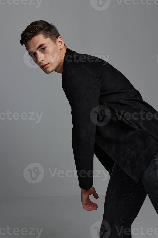 A man in a dark suit on a gray background leaned to the side for a cropped view photo
