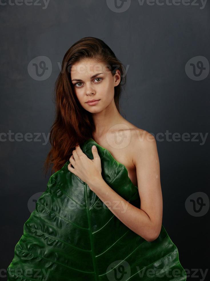 pretty woman covers naked body with palm leaf exotic isolated background photo