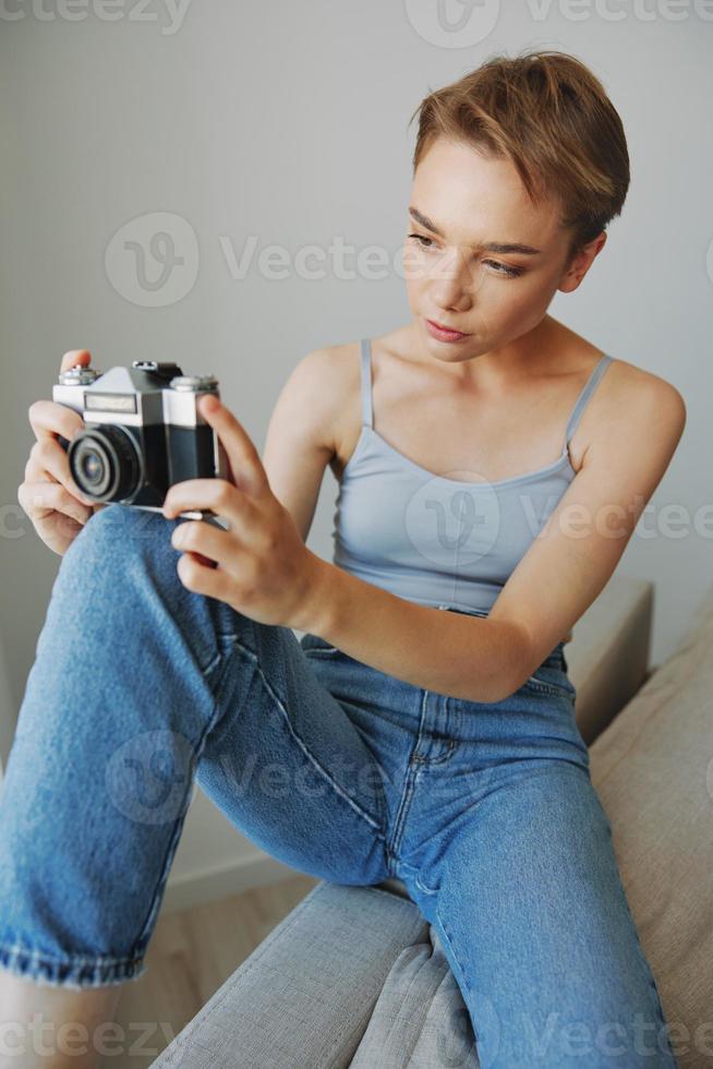 Woman photographer shooting in studio on old film camera at home on couch portrait, white background, free copy space, freelance photographer photo