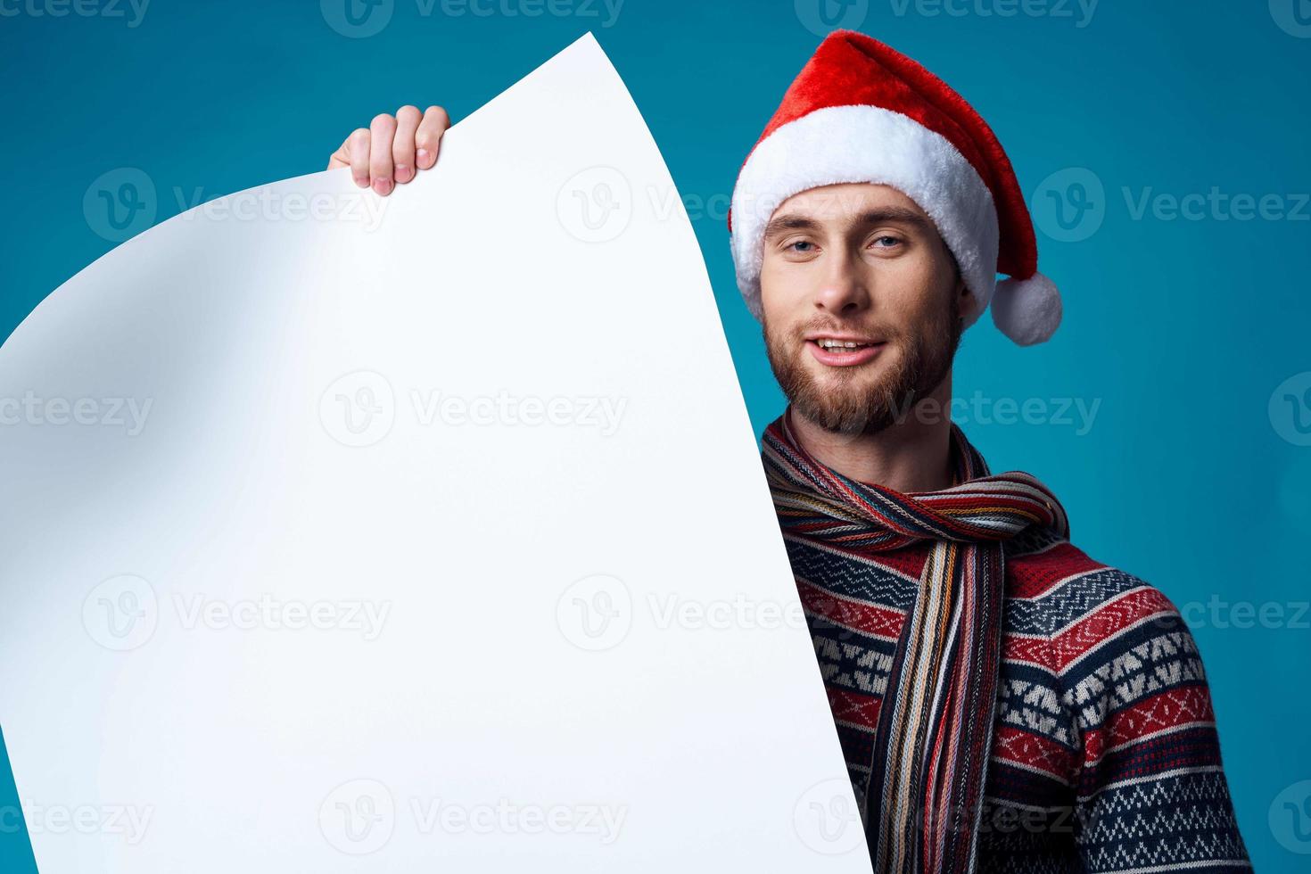 handsome man in a santa hat holding a banner holiday blue background photo