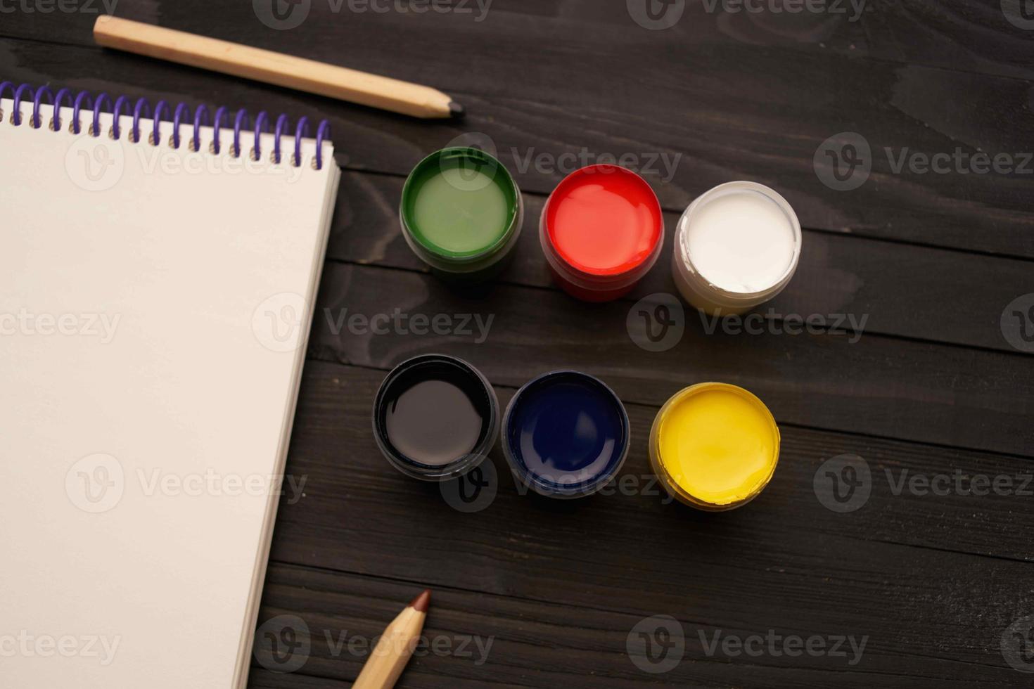 watercolor paints pencils notepad drawing tools art dark wood background photo