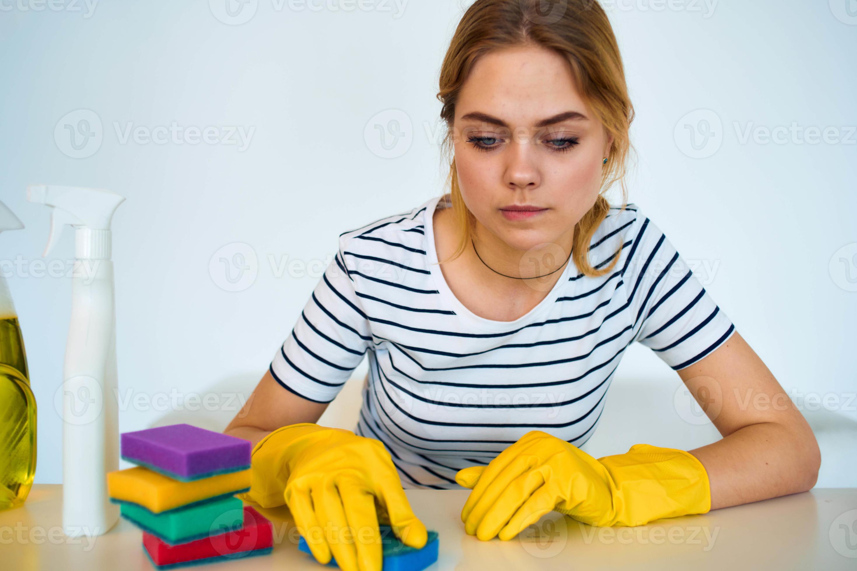 Cleaning lady sitting at the table with detergent sponge rubber gloves