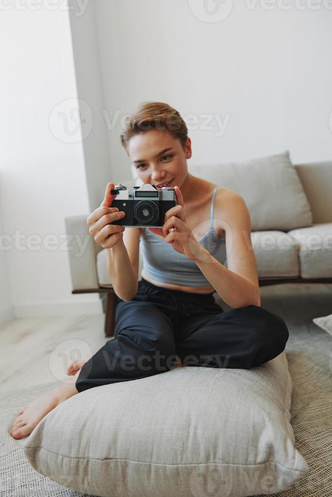 Happy smile woman holding an old camera and taking pictures of herself as a weekend photographer in home clothes with a short haircut hair without filters on a white background, free copy space photo