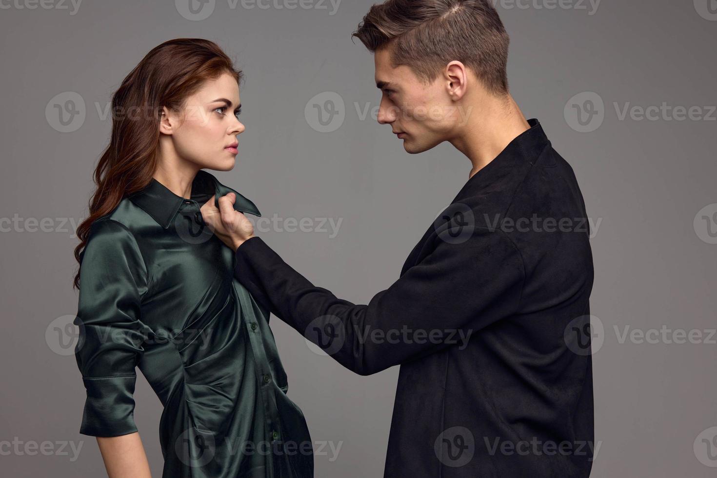 A woman in a silk dress and an aggressive man in a suit on a gray background look at each other photo