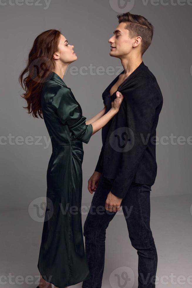 A man in a classic suit looks at a beautiful woman in a dress on a gray background photo