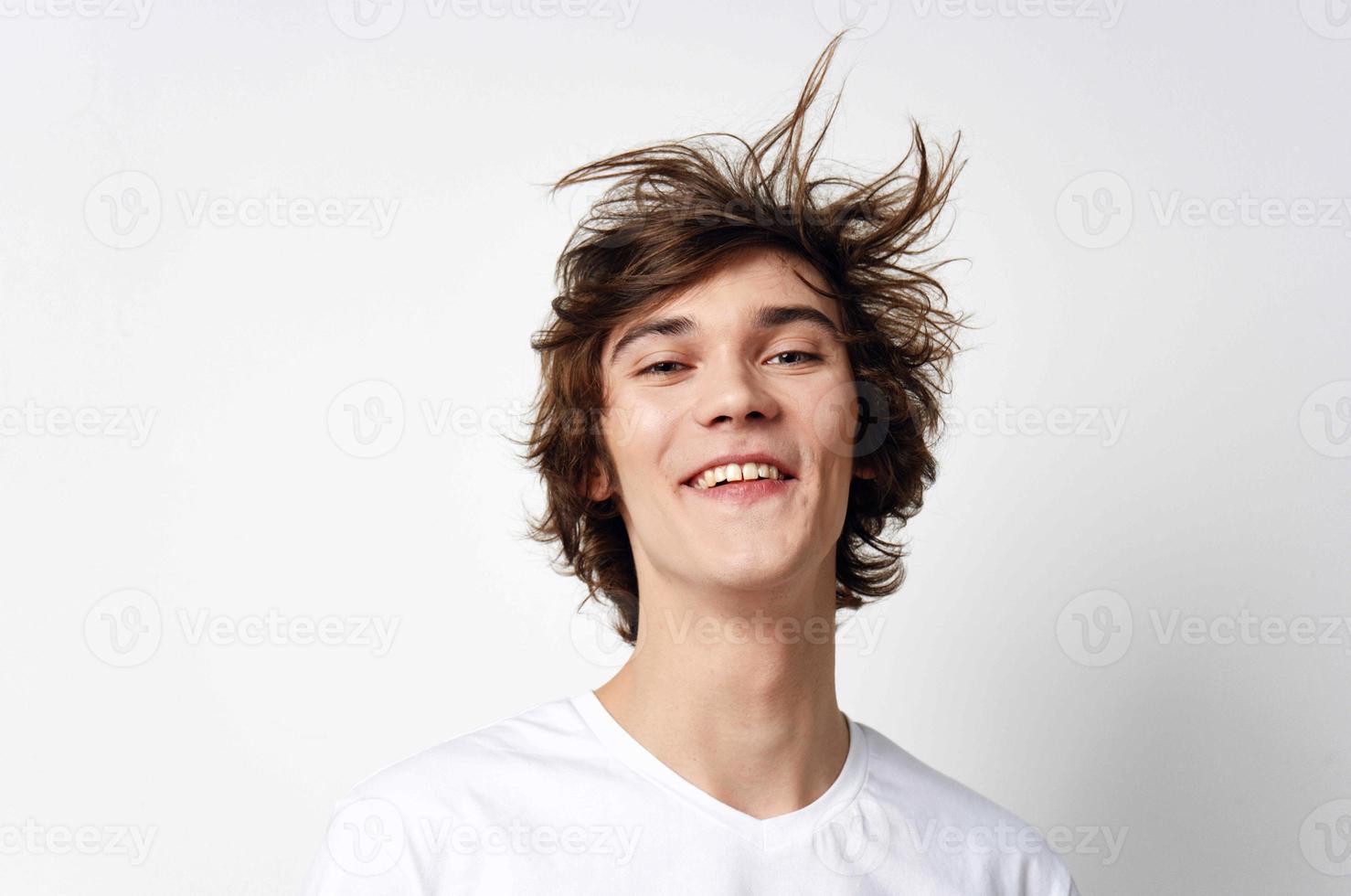 alegre chico con despeinado pelo en un blanco camiseta emociones de cerca foto