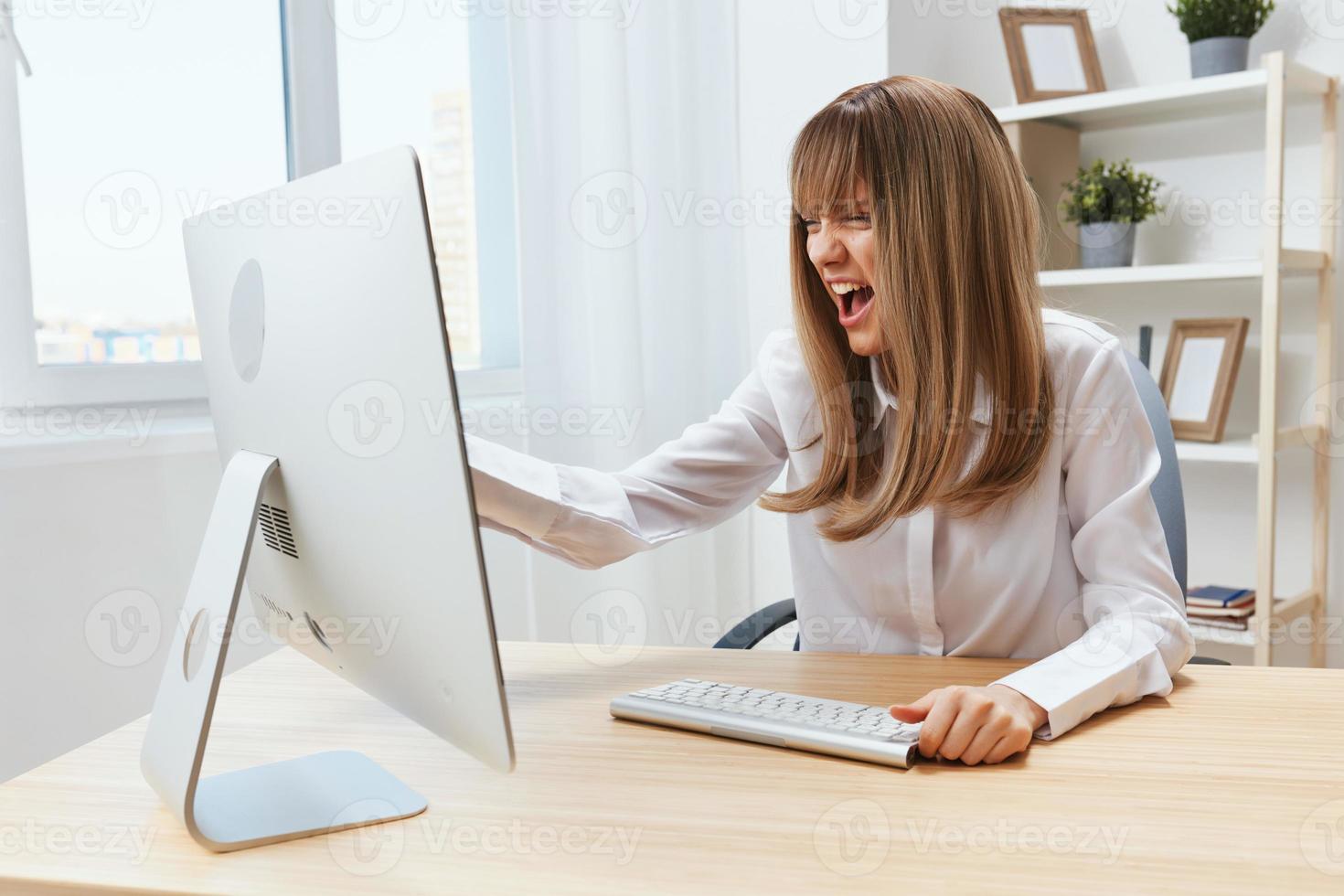 Angry evil blonde businesswoman screaming to desktop Raging after computer software crash error at workplace in modern office. Irritated director work online in financial corporation. Copy space photo