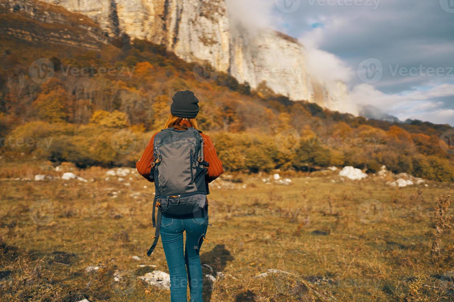 woman in autumn resting in nature in the mountains sun blue sky landscape backpack photo