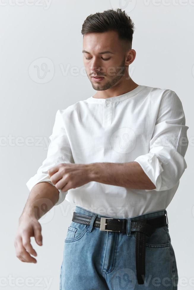 Handsome attractive serious model man guy wear linen shirt rolling up sleeves posing isolated on white studio background. Fashion Style New Collection Sale ad concept. Copy space, banner. Model shoot photo
