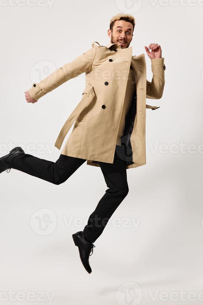 man in beige coat autumn style jump studio light background photo