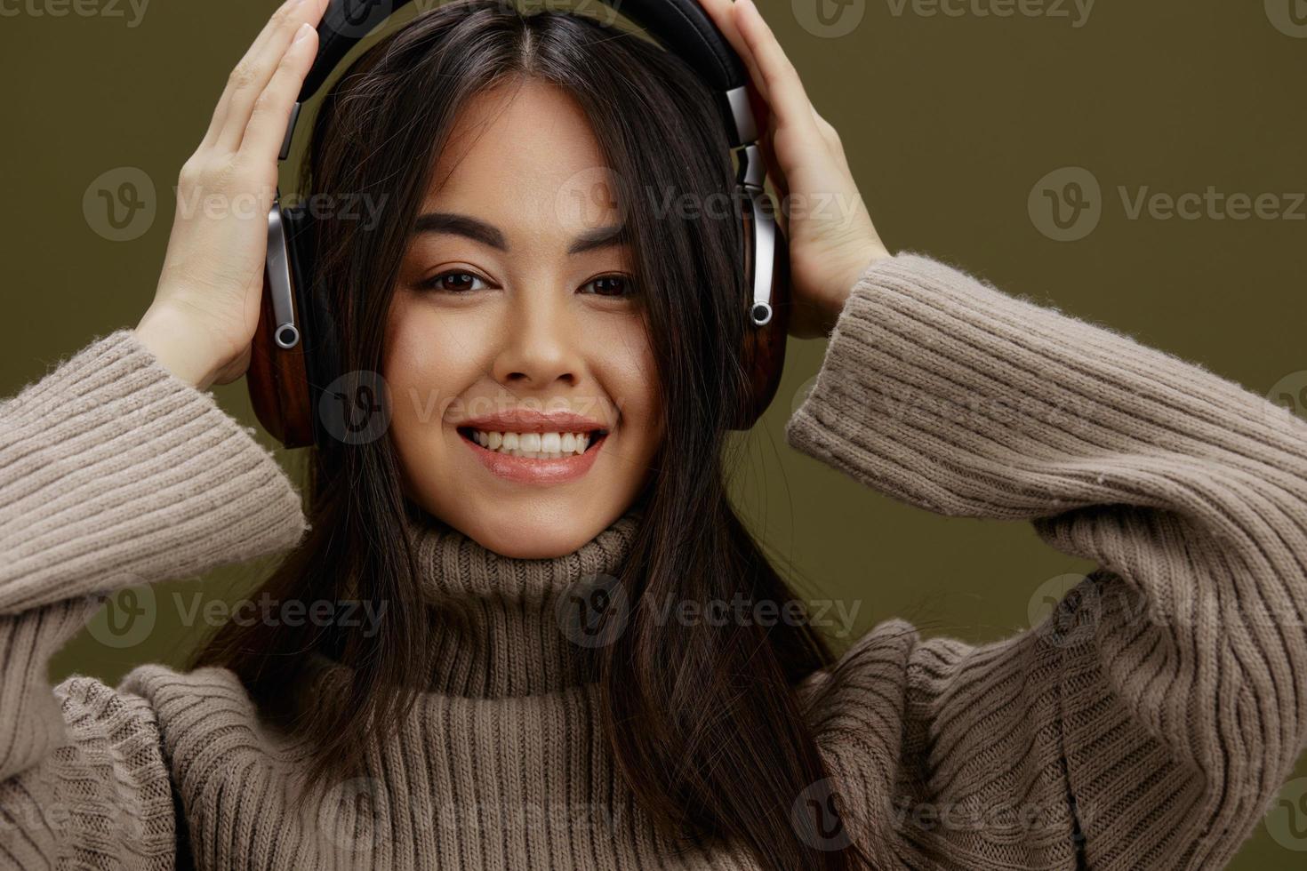 woman in a sweater listening to music with headphones fun isolated