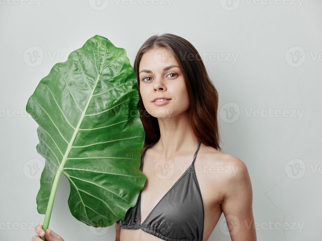 woman in gray swimwear palm leaf in hands attractive look cropped view photo