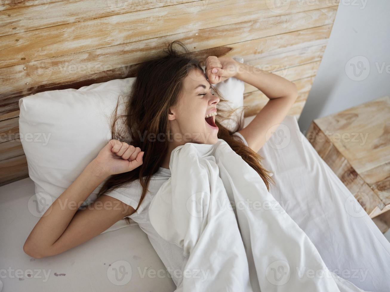 happy woman waking up in bed yawning photo