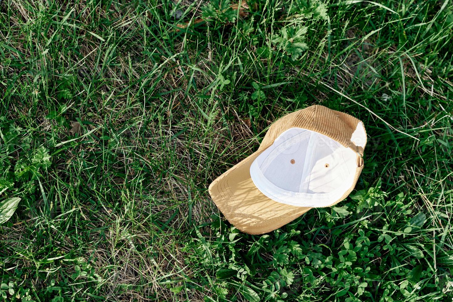 A yellow sports cap lies upside down on the green grass. Spring outdoor sports games photo