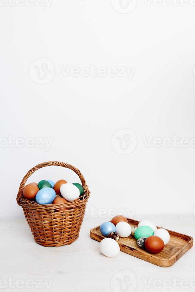 Easter holiday in colored eggs in a basket and on a wooden board In a bright room photo