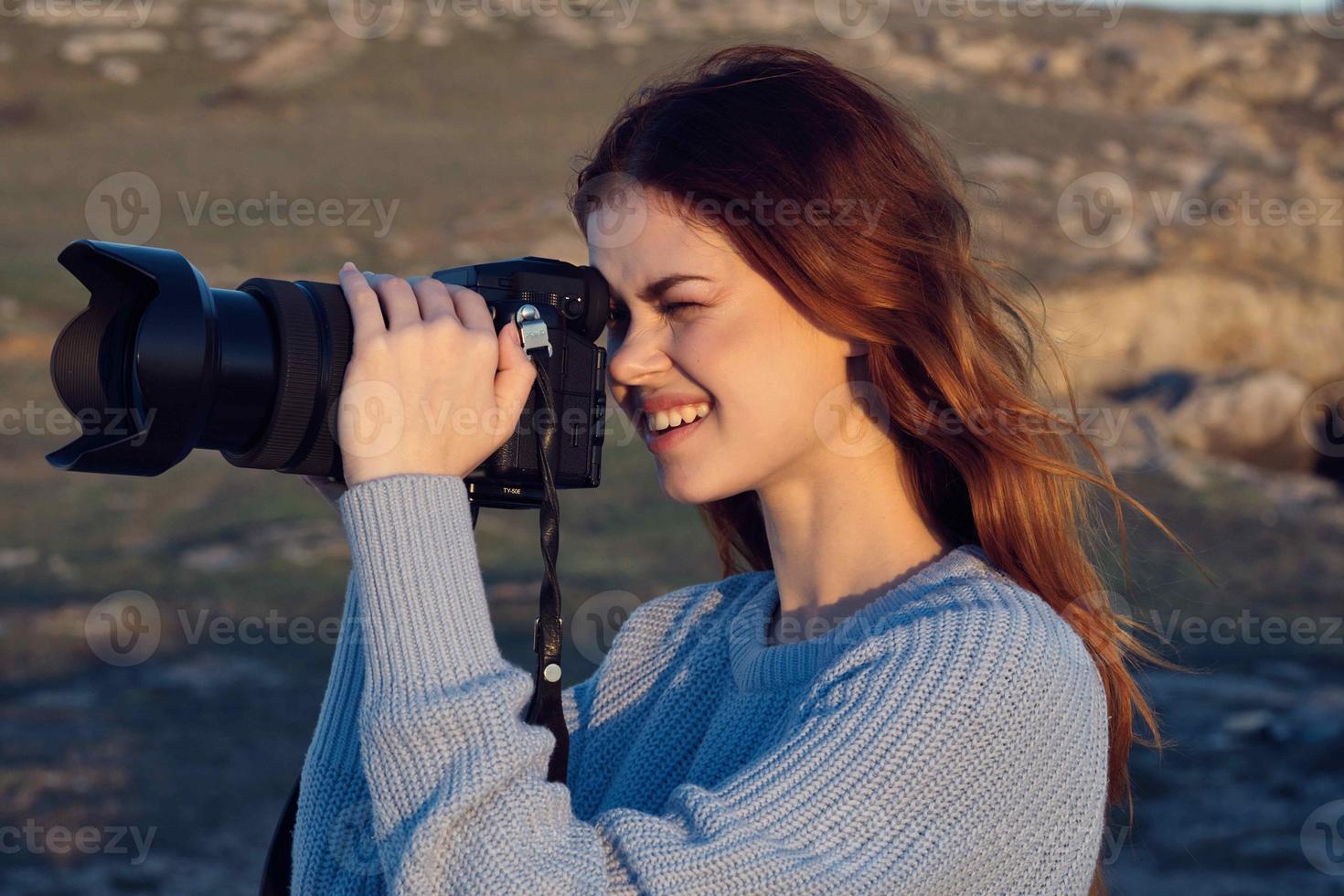 mujer con cámara en naturaleza tomando imágenes de paisaje profesional foto