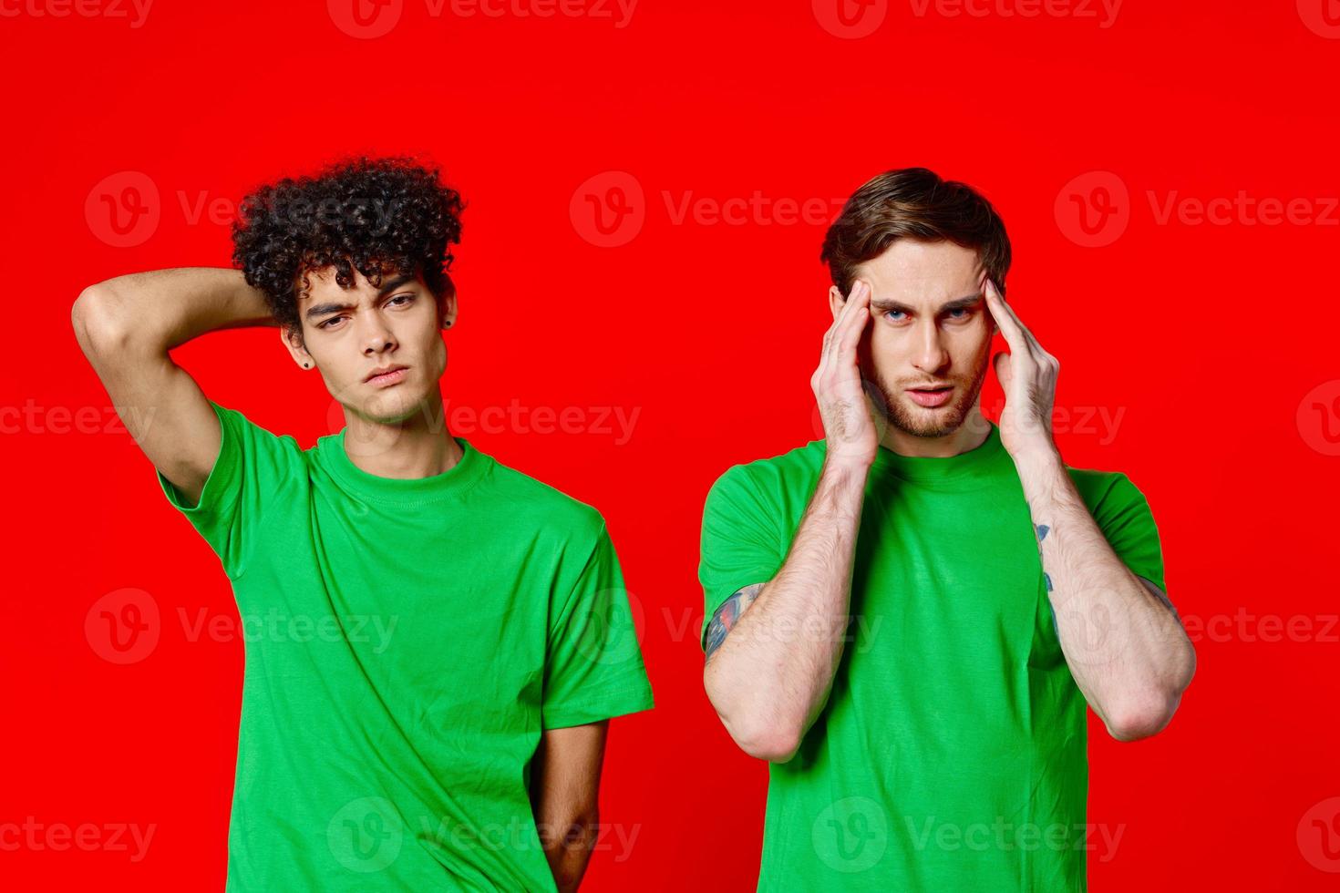 two men holding their heads in green T-shirts on a red background photo