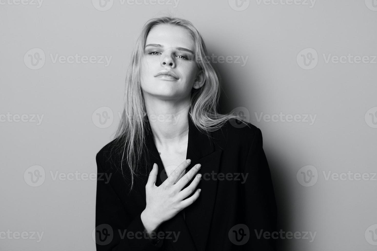 Sexy expressive professional model touching her jacket and looks at camera. Beautiful blonde lady posing at studio. Good offer for fashion brands. Minimalistic art style photo