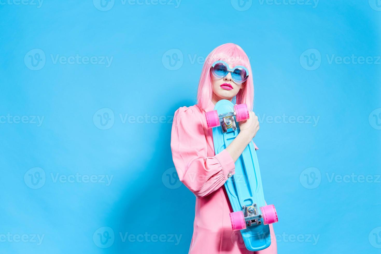 portrait of a woman with skateboard in pink wig blue background photo