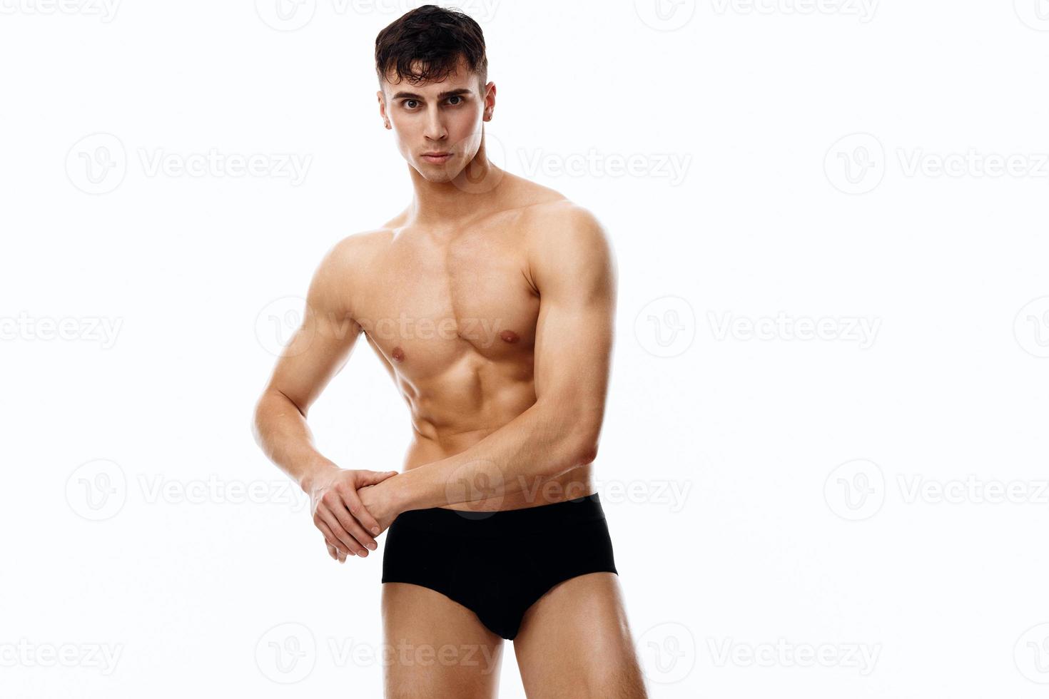 young guy athlete with a pumped-up torso gesturing with his hands on a light background photo