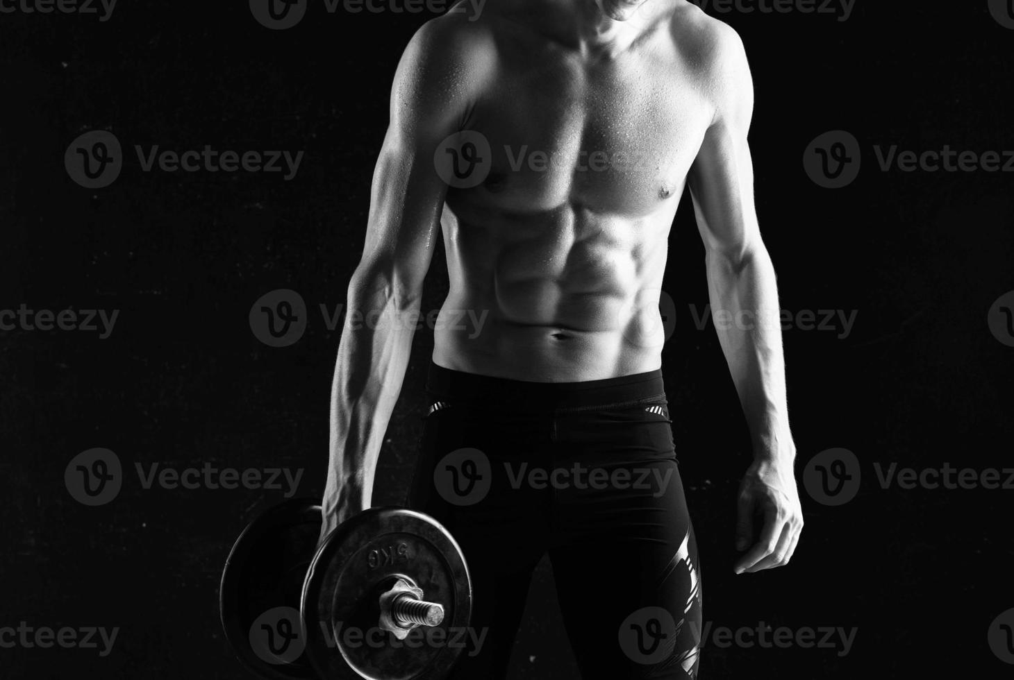 man with dumbbells in his hands naked muscular body workout dark background photo