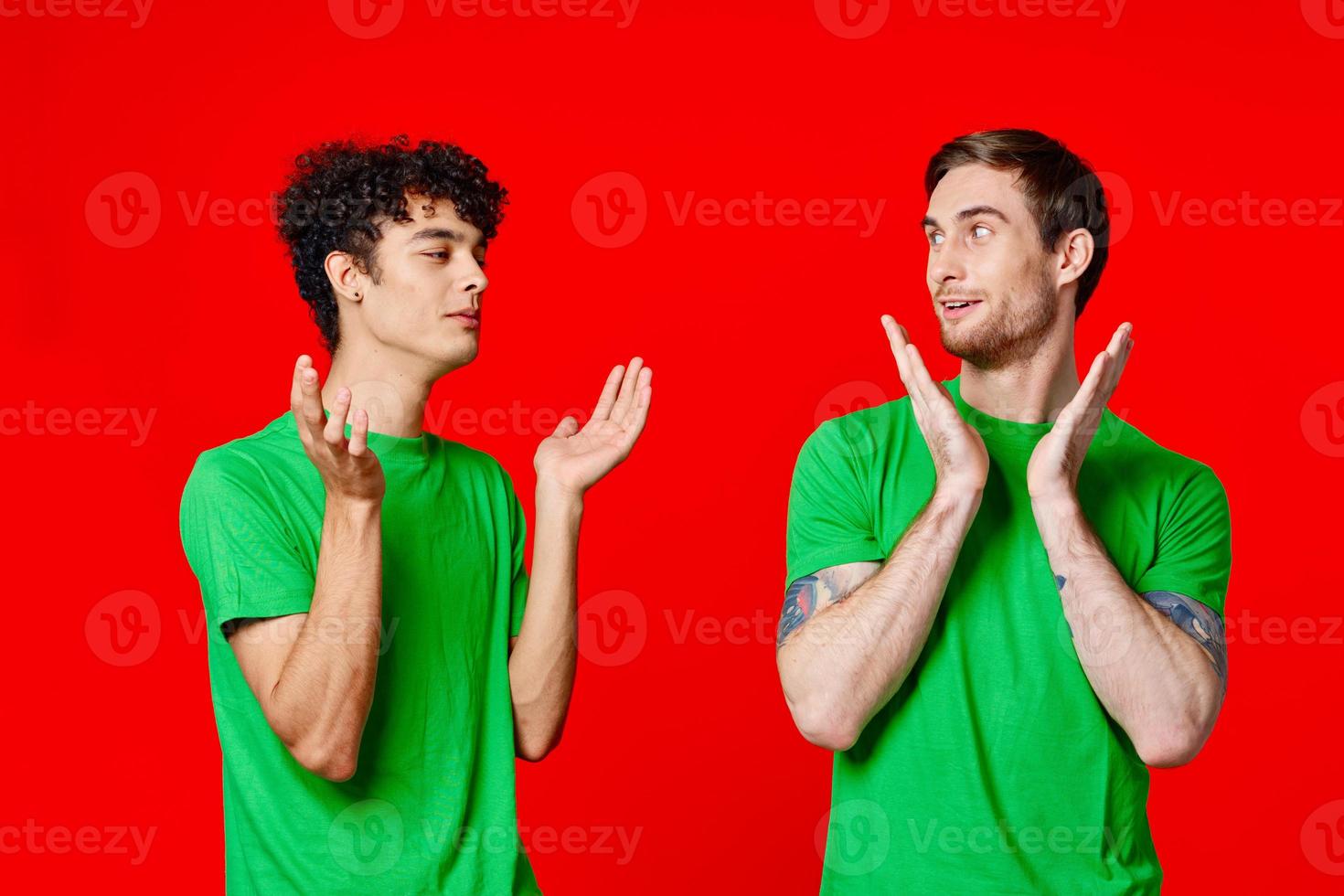 two men holding their heads in green T-shirts on a red background photo