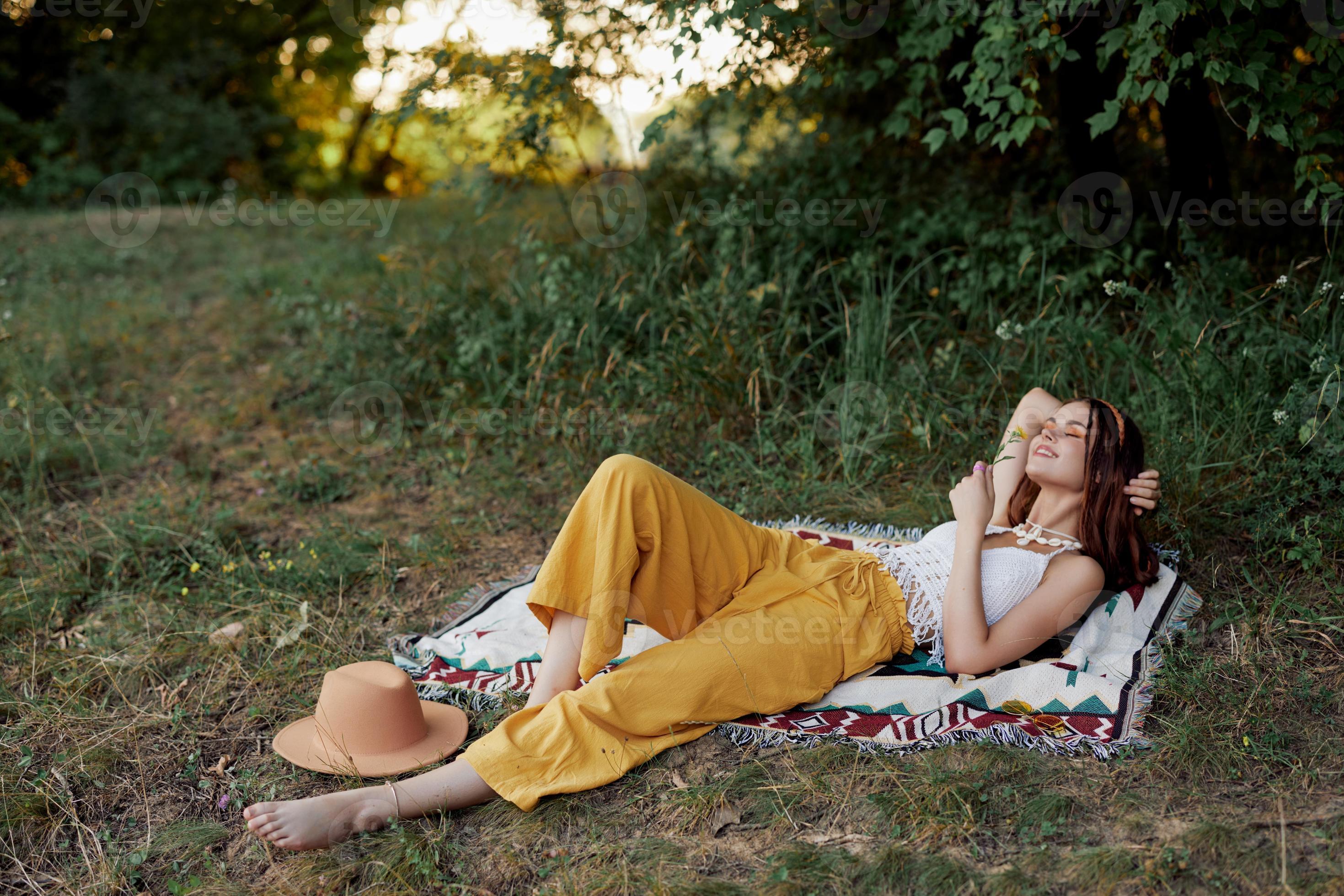 Young beautiful hippie woman lying on the ground in nature in the fall ...