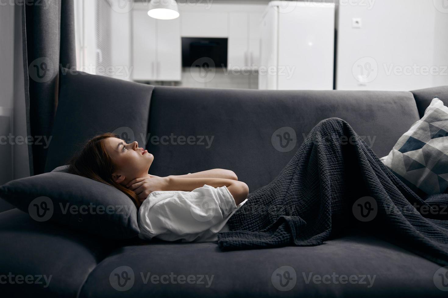 woman covered with a blanket is resting lying on the sofa photo