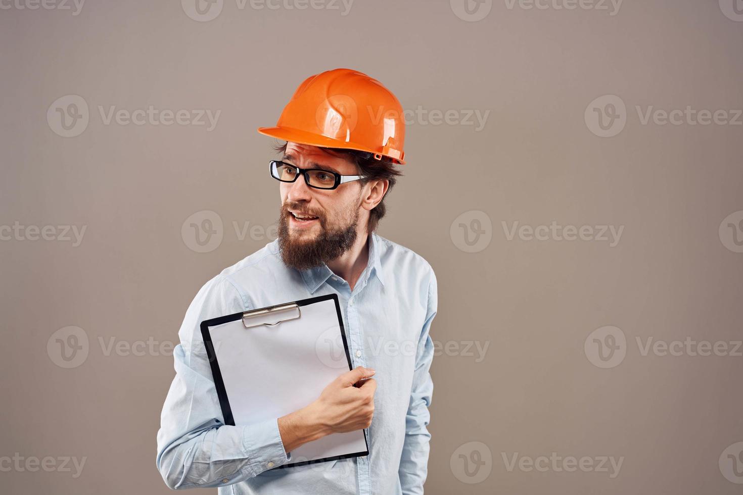 A man in orange paint with documents in hands building an industrial business photo