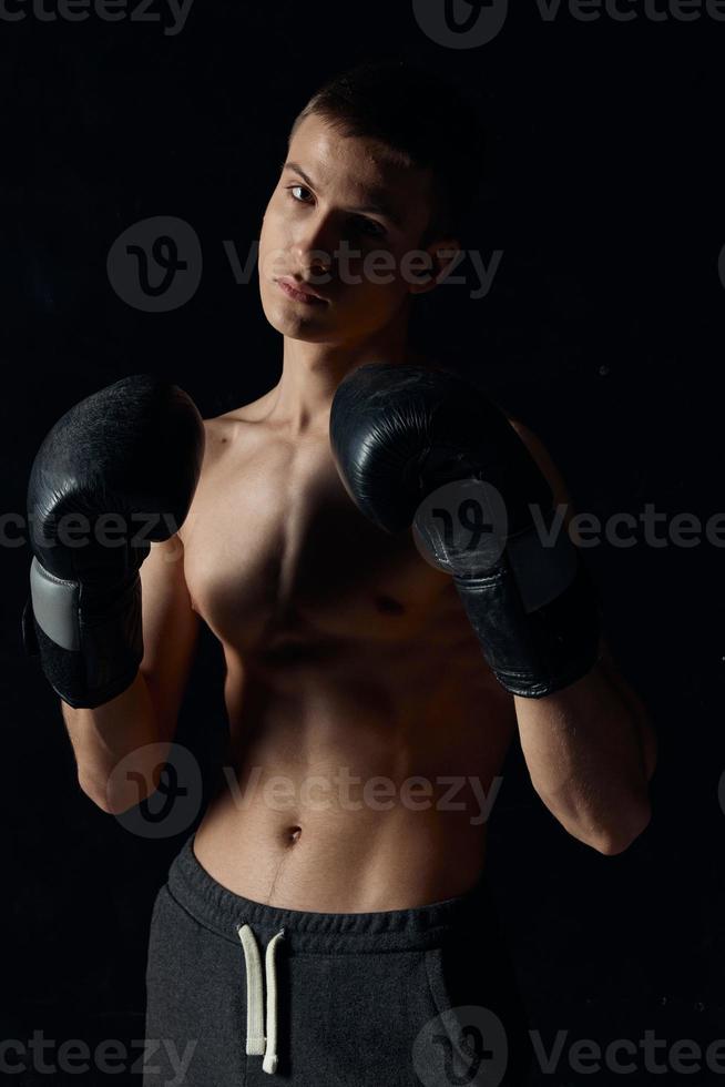 sports guy on a black background in boxing gloves inflated torso cropped view Model Copy Space photo
