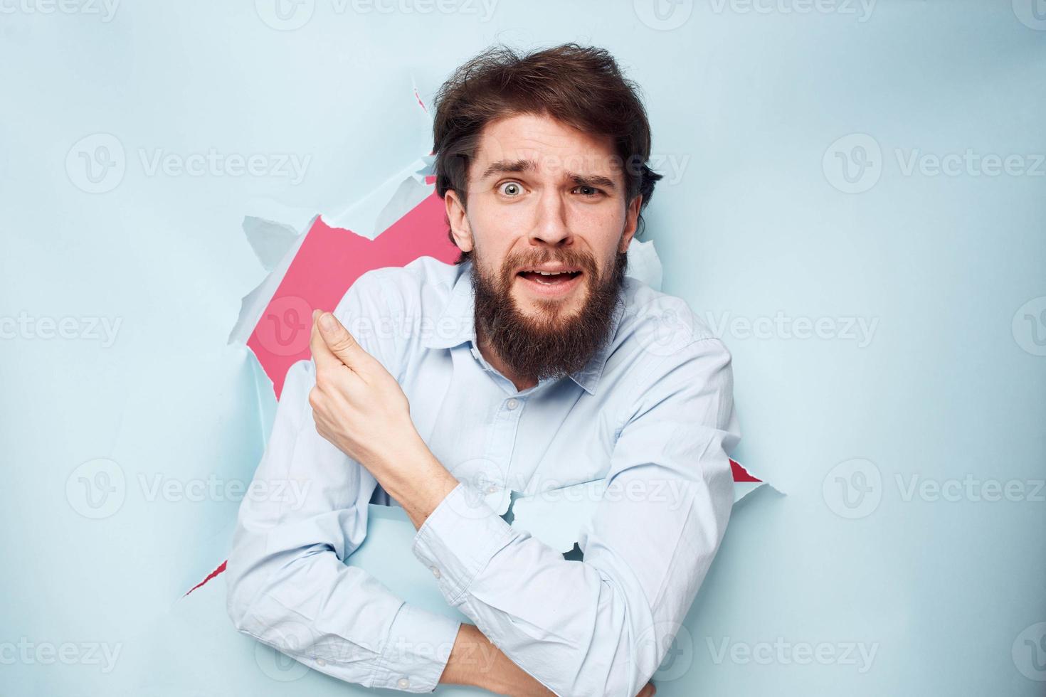 Emotional bearded man peeks out from behind the wall in office work shirt photo